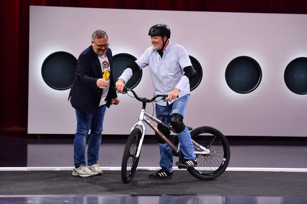 Zwei Männer mit einem BMX-Rad in einem TV-Studio