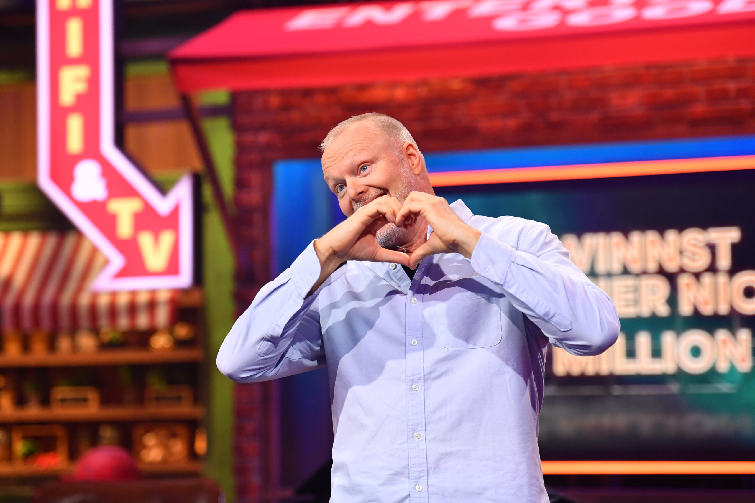 Mann formt mit den Händen ein Herz im Studio von „Du gewinnst hier nicht die Million“